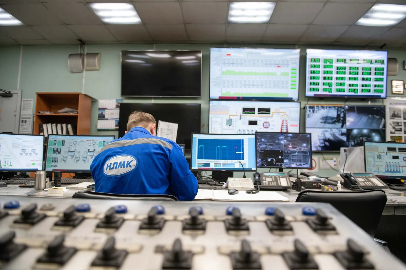 An operator working across a bank of monitoring screens